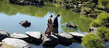 枯山水の飛び石を手を繋いで歩く新郎新婦