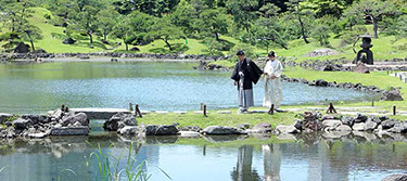 枯山水の飛び石を手を繋いで歩く新郎新婦